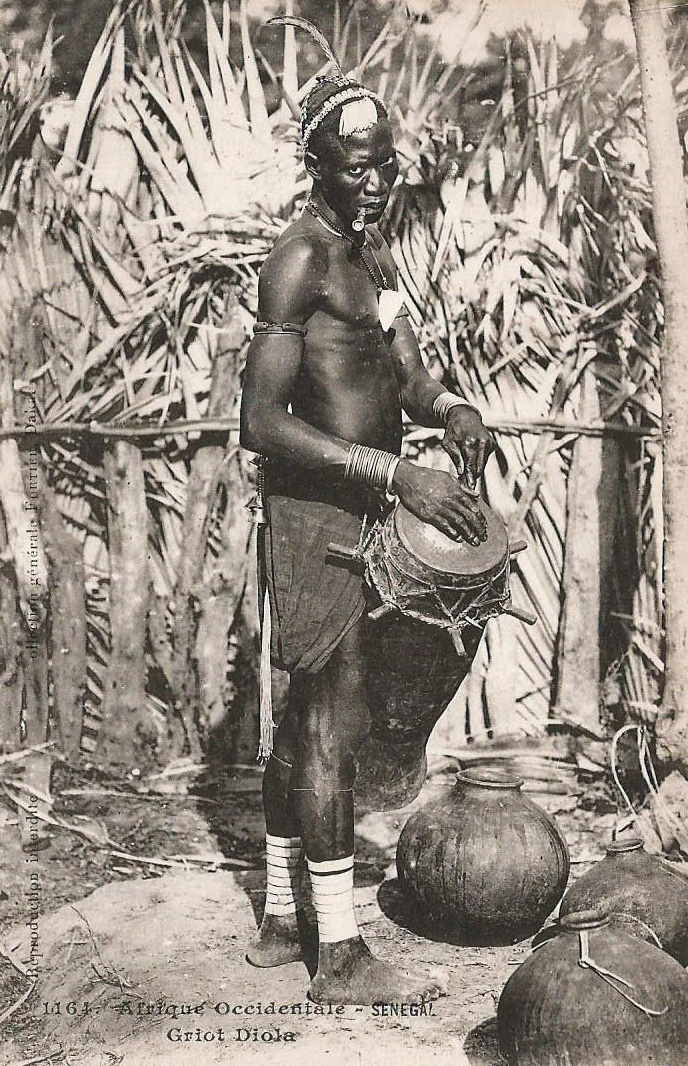 Griot senegalês, de etnia diola, tocando um sabar. Fotografia de François-Edmond Fortier (1862-1928). Domínio Público.